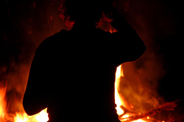 a man is looking up as he stands in front of a blazing fire