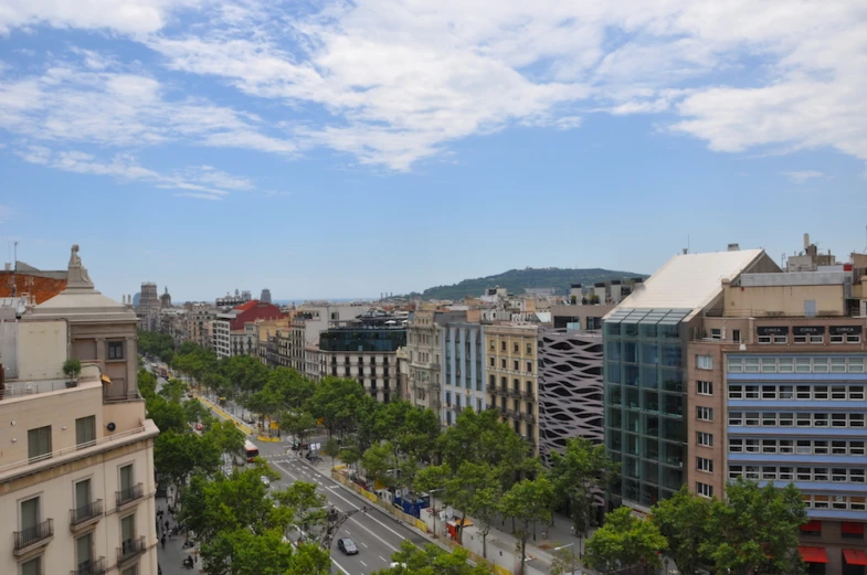 a wide urban street with tall buildings on the opposite side of a road