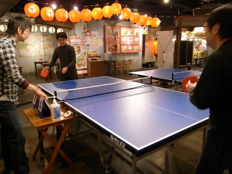 several men are playing ping pong in a mall