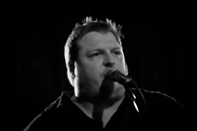 a man is singing into a microphone while wearing a black shirt