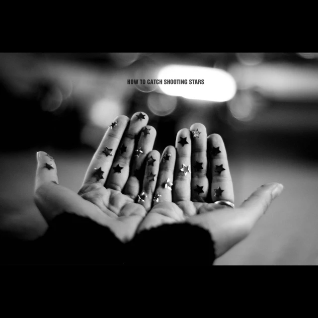 a black and white image of three female hands with stars on them