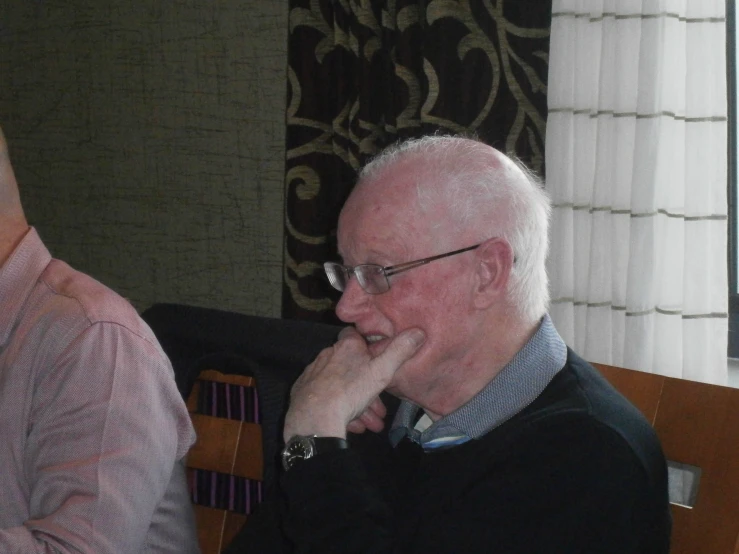 a man sitting on top of a chair while holding his hands to his face