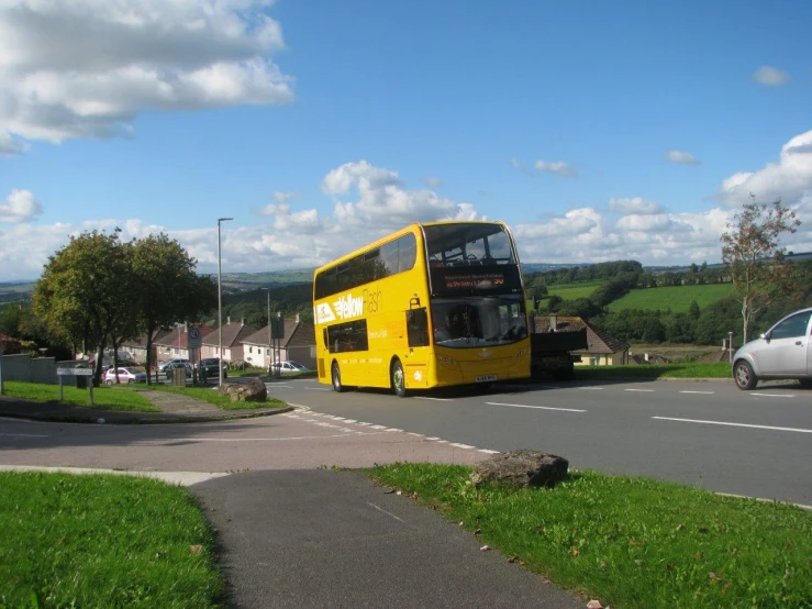 a yellow double decker bus riding down the street