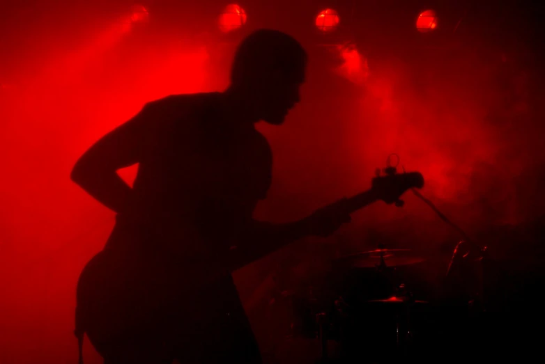 a man with a guitar standing against a microphone