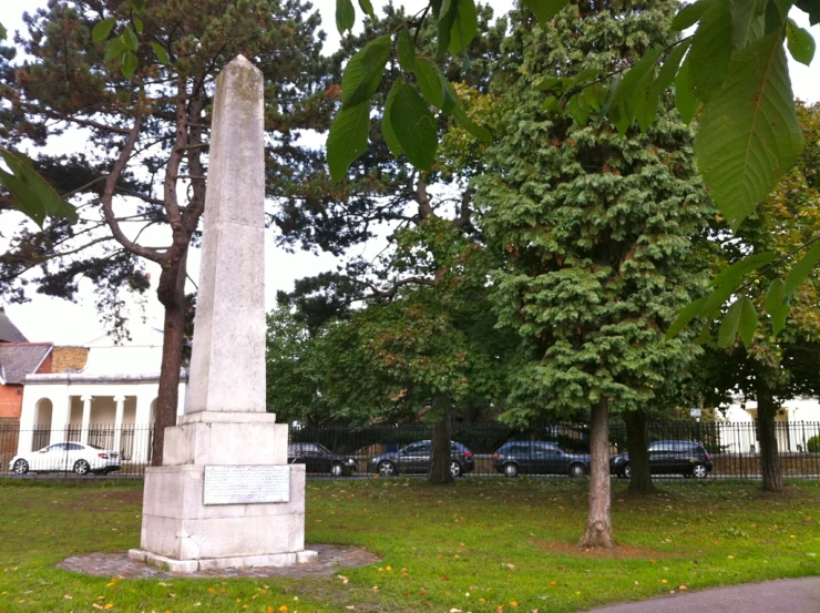 the monument is surrounded by tall trees near a fence