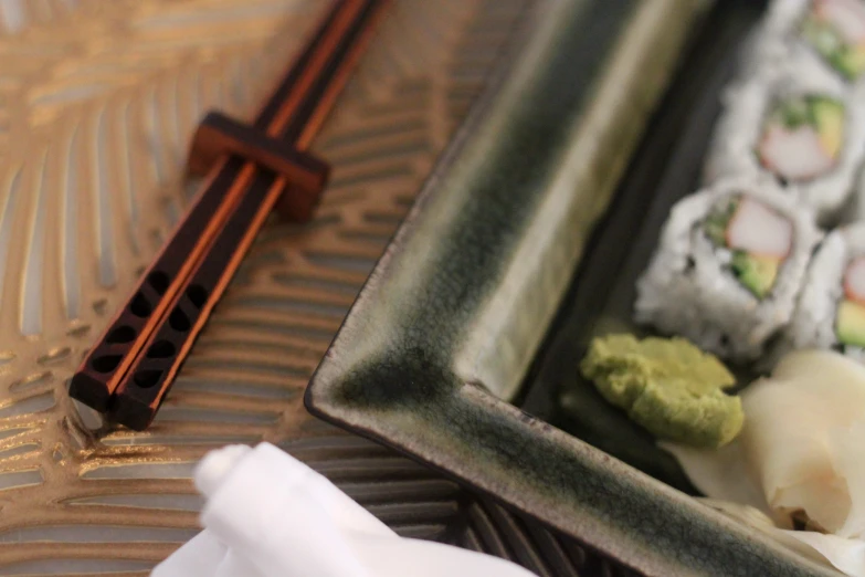 a small tray filled with sushi next to some chopsticks