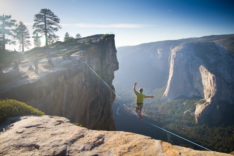 a man is standing on the rope above the mountain