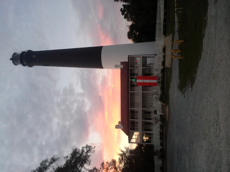 a very tall black and white lighthouse with a big red door