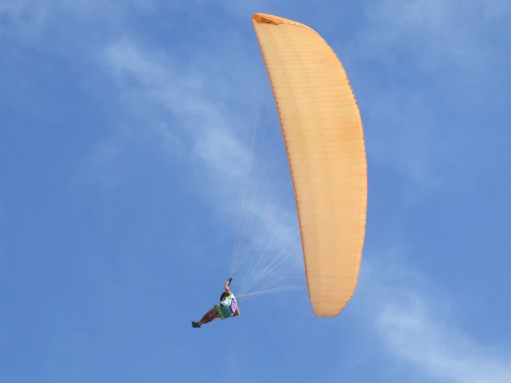 a person flying a yellow kite through a blue sky