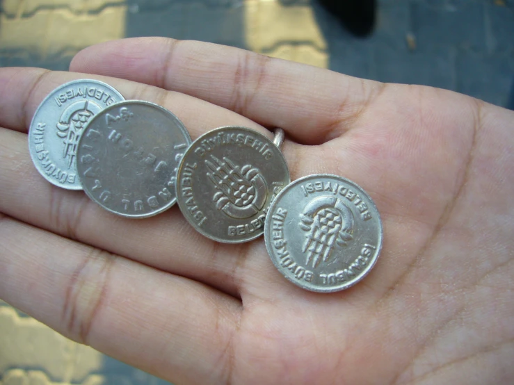 three silver and one coin in someones hand