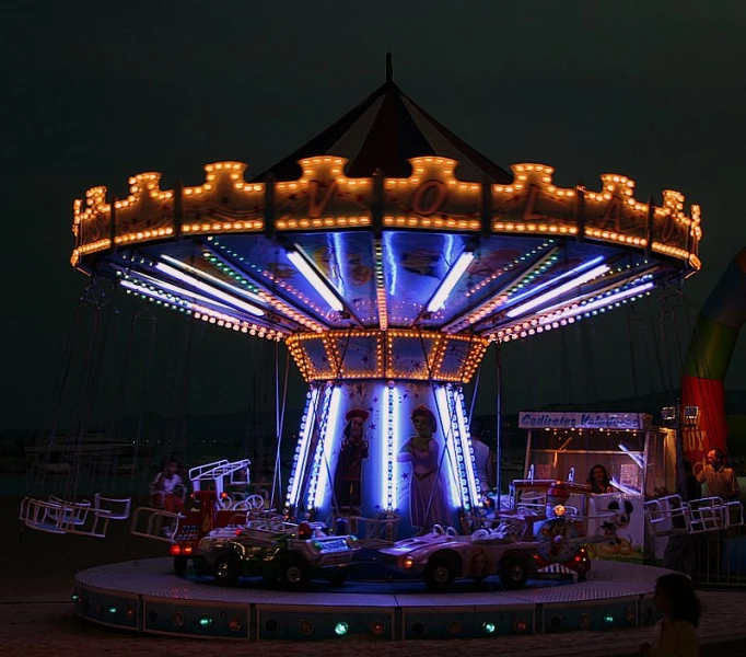 a carnival ride with people standing around and lights on it