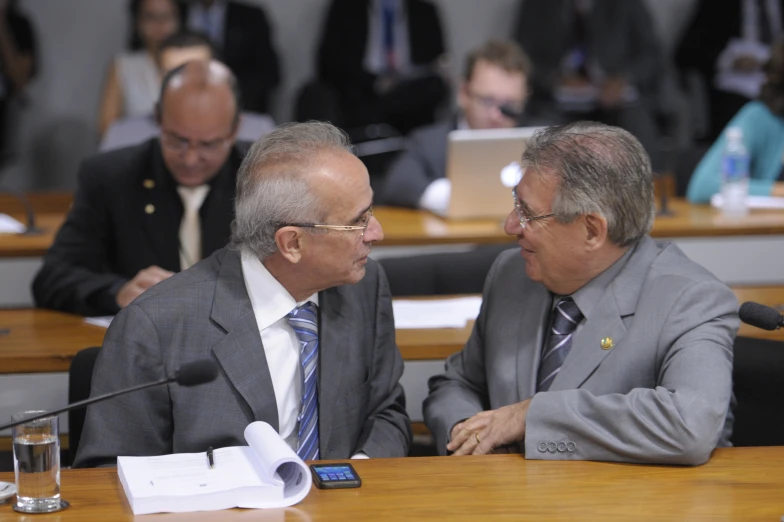 two men sitting at a table talking together