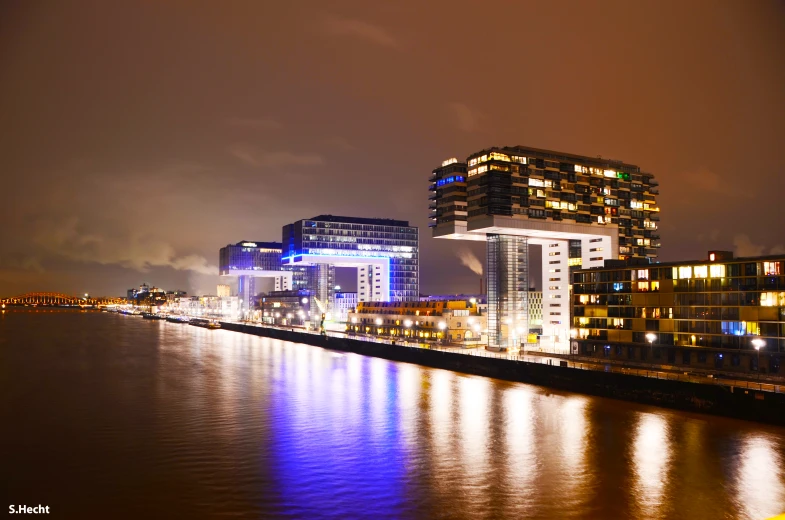 a long stretch of water at night with city lights reflecting off of the buildings