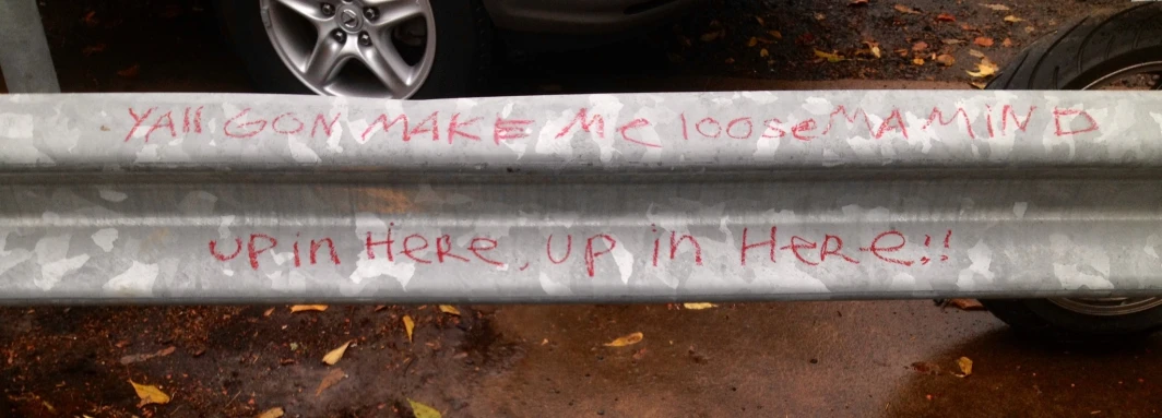 two metal tubes with graffiti on them sit next to some parked cars