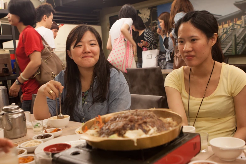 two women sitting at a table with food