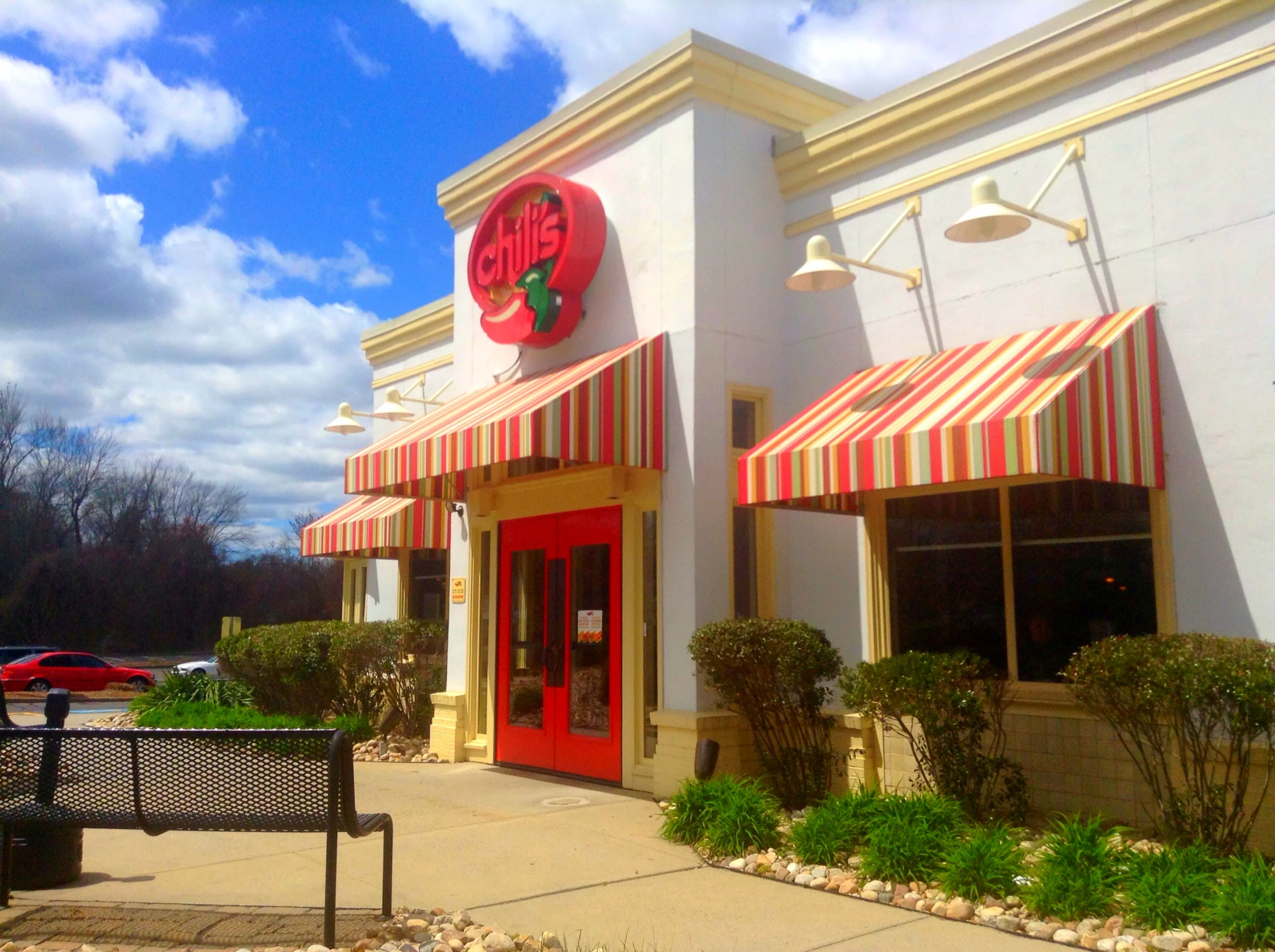 the exterior of a restaurant with a red door and striped awning