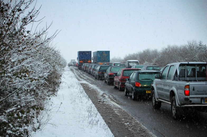 several cars are lined up on the side of the road in heavy snow