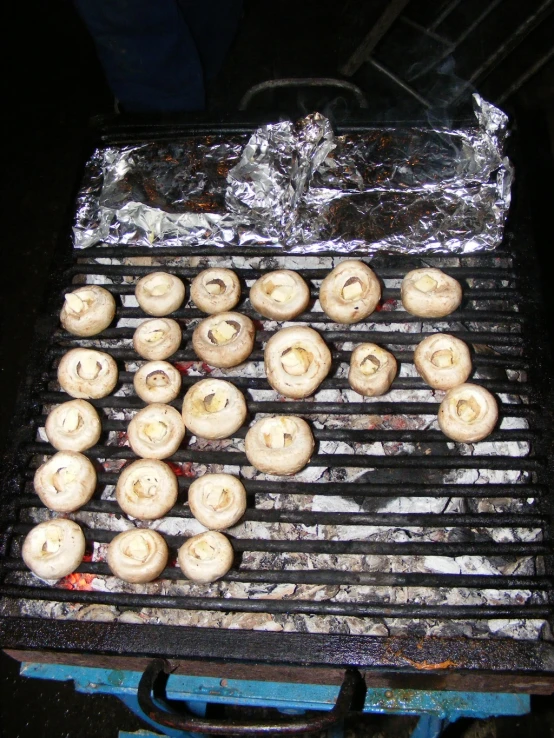 donuts cooking on an outdoor grill that is covered with foil