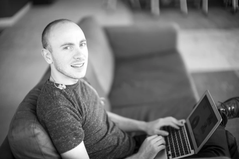 a black and white po of a man sitting with his laptop on his lap