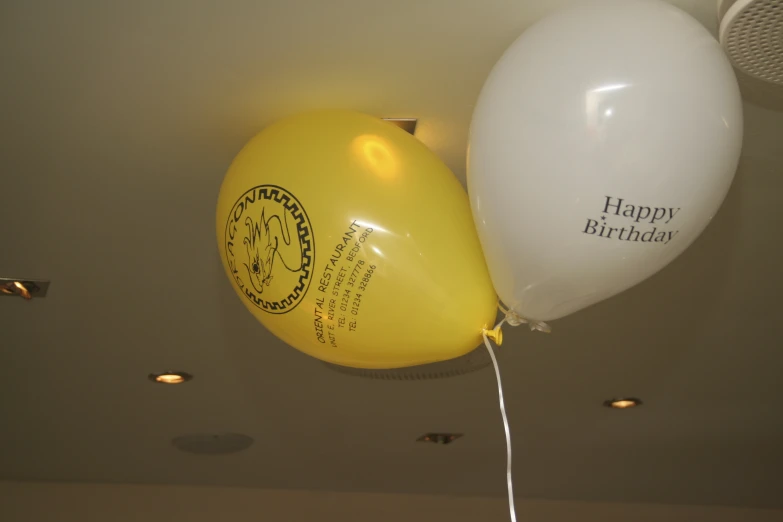 a couple of white and yellow balloons hanging from a ceiling