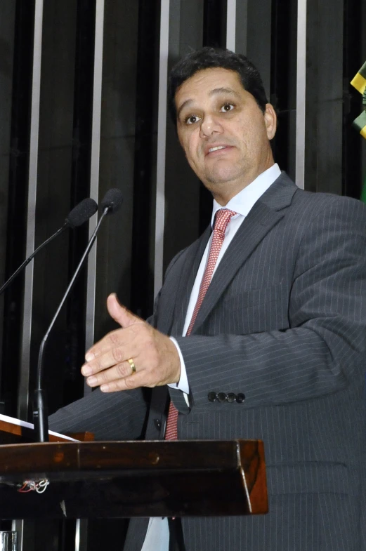 man speaking at podium with flag behind him