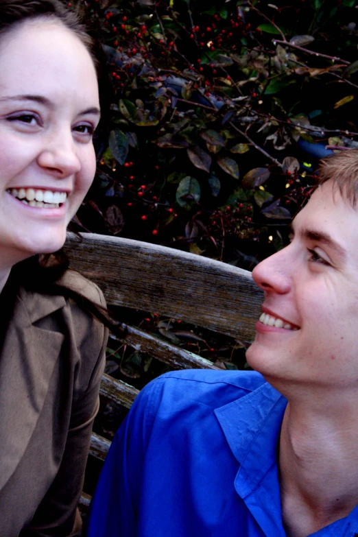 a woman smiling next to a man on a park bench