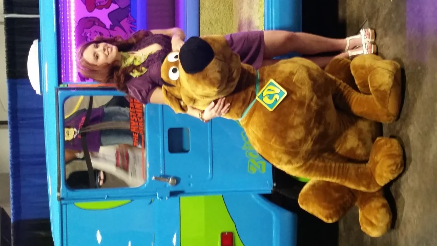 a woman in purple is posing with a dog mascot