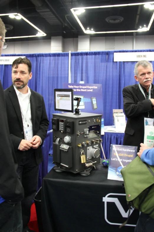 men looking at an electronic device that is on display