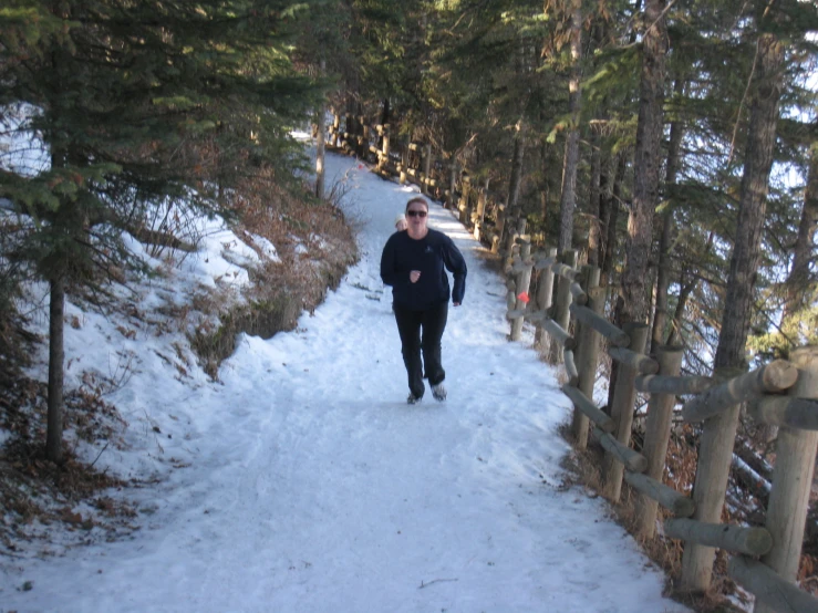 man walking on a trail between the snowy forest