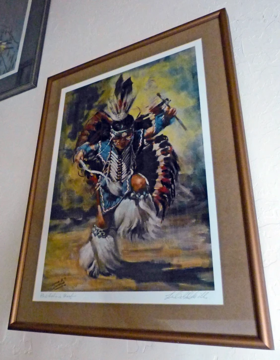 a painting hangs above a frame on the wall