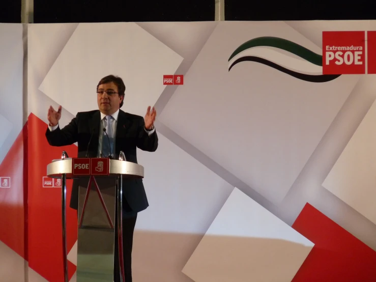 a man in a suit stands at a podium giving a speech