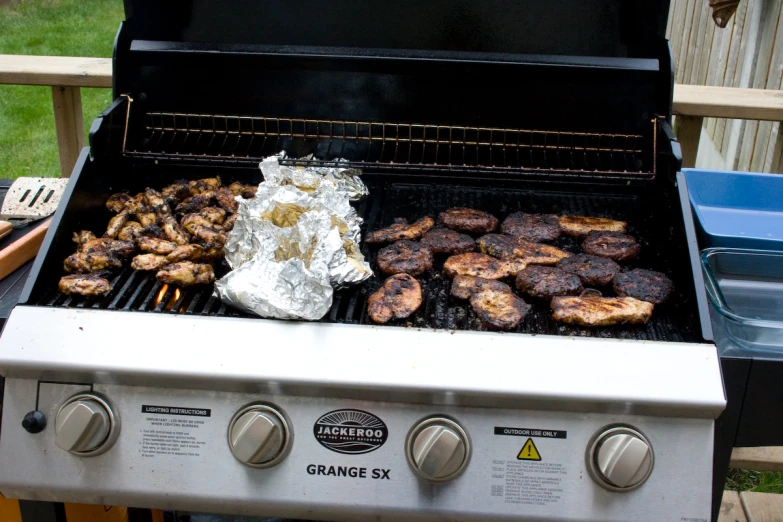 a person is cooking hamburgers and grilled chicken on an outdoor grill