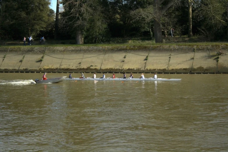 people rowing in long boats on water near wall