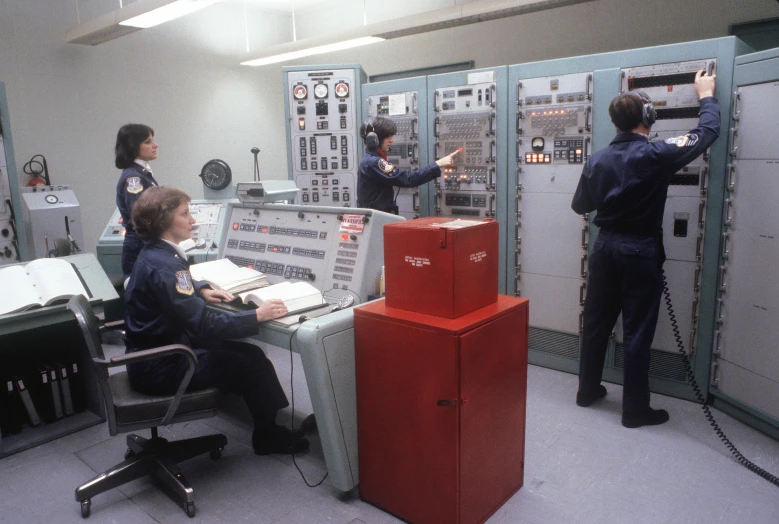 three pilots are setting up controls in a control room