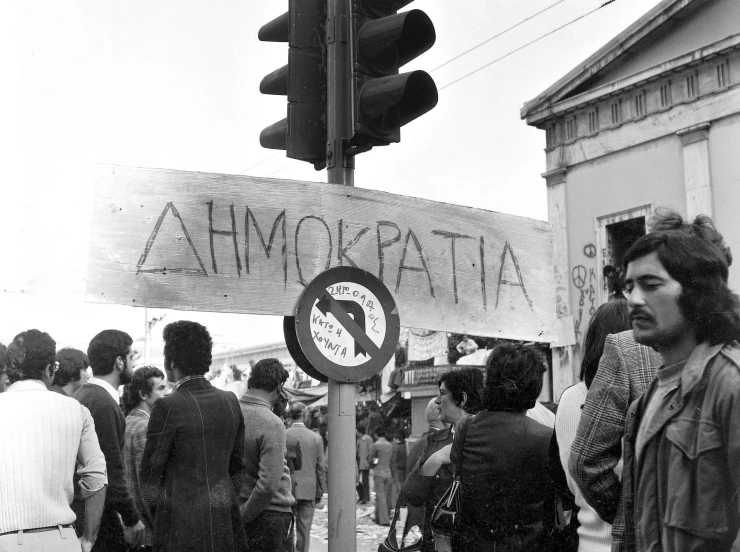 a black and white image of people waiting to cross the street