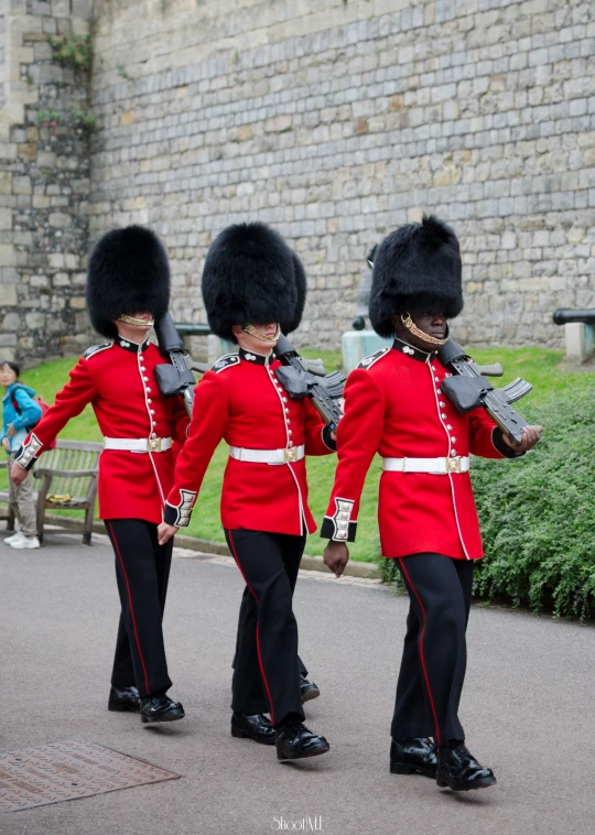 three guards in british uniforms marching down the street