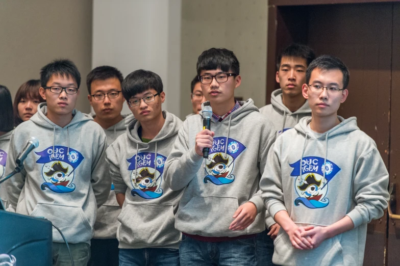 group of guys in matching sweatshirts holding a large microphone