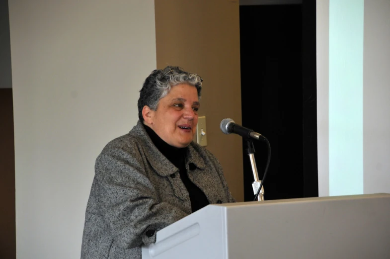 the lady has white hair and is standing at a podium