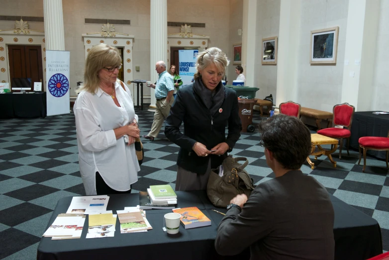 three women are looking at pos and papers on the table