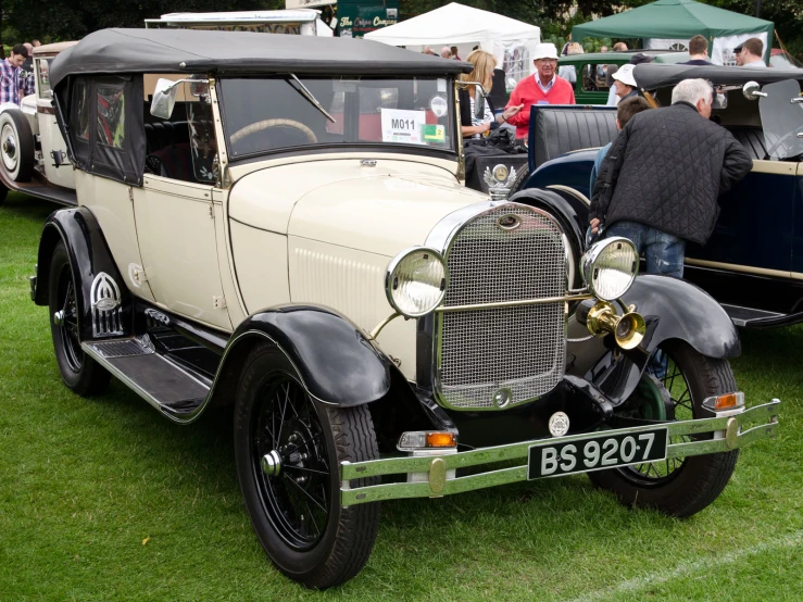 a vintage car at a show with people standing around