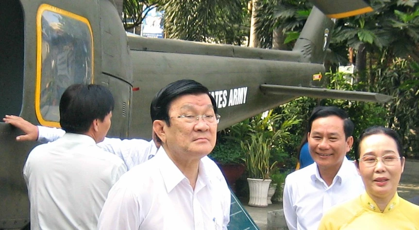 some men are standing by some trees and an airplane