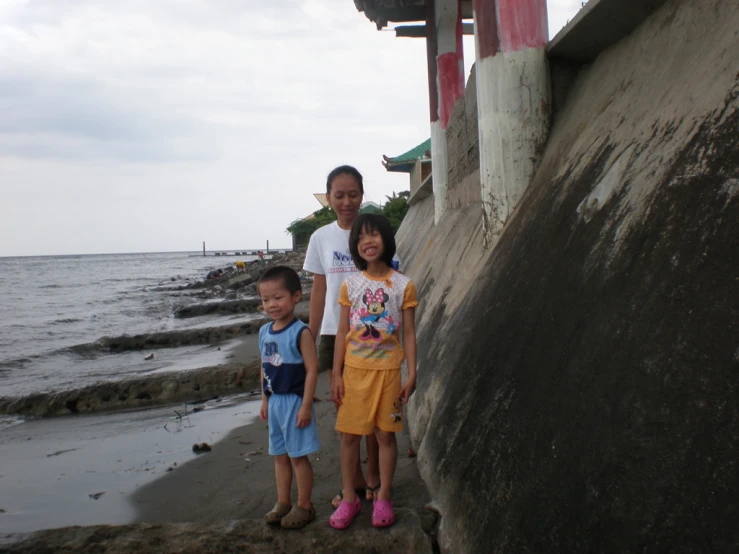 three children walking on the beach by the water