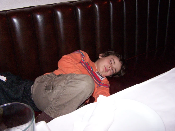 a little boy laying on top of a bed with a brown pillow