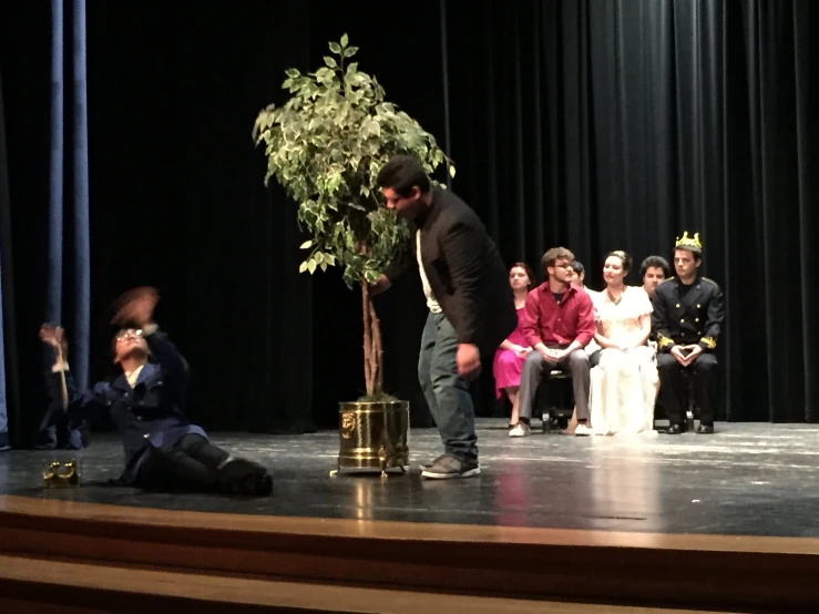 a man with a flower in his hand by some people on stage