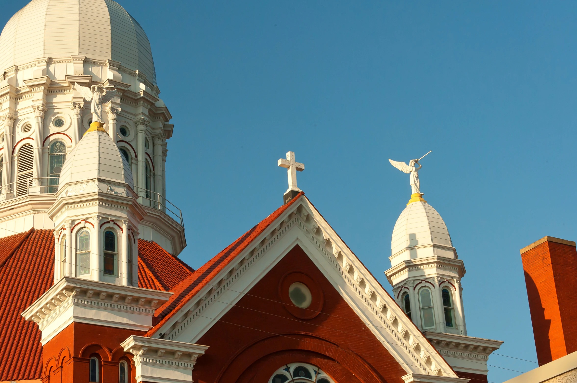 a white church with red roofs, an arrow and two crosses