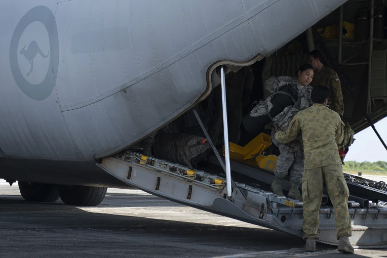 two men in uniform load items onto a large airplane