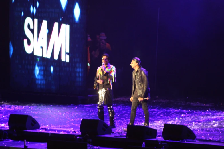 two people standing on a stage with lights on