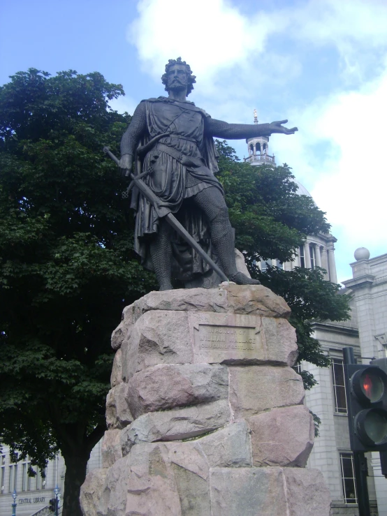 a statue sitting on top of a rock next to a tree