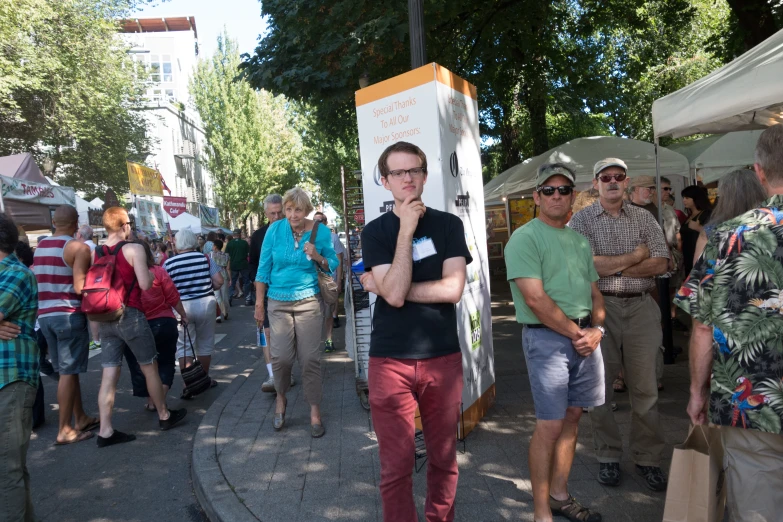 man standing on the sidewalk while other people walk along