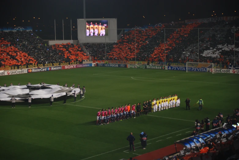 many teams are gathered in front of a large speaker screen